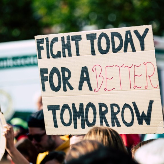 Person holding a sign that says "Fight today for a better tomorrow."