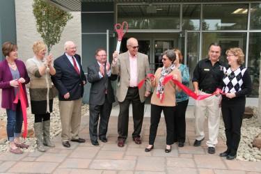 A line of people celebrating a ribbon cutting ceremony.
