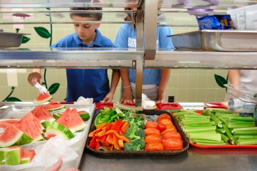 Children selecting fresh produce in a cafeteria line.