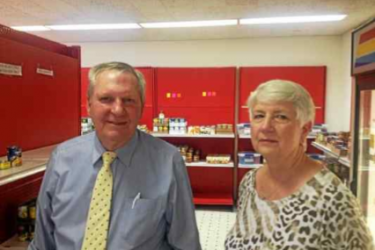 Two people in front of food pantry shelves.