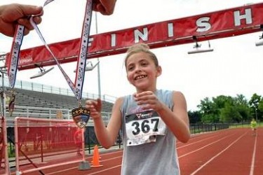 A girl accepts a medal for finishing a foot race.