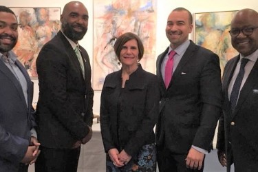 Four men of color and one Caucasian woman, all in suits, posing for a picture.