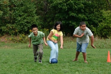 Three kids playing with a soccer ball.