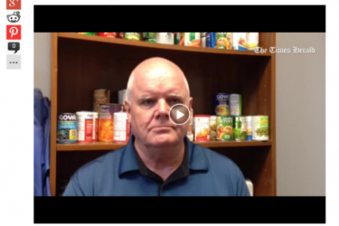 Still of a video of a Caucasian man in front of shelves with canned goods.