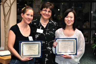Three women posing for the camera, two hold up certificates.