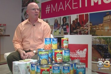 A Caucasian man sitting behind canned food.